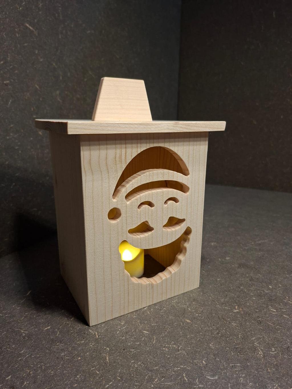 Drei handgefertigte LED-Weihnachtslaternen aus hellem Holz mit ausgesägten Motiven Weihnachtsmann, Tannenbaum und Kerze.