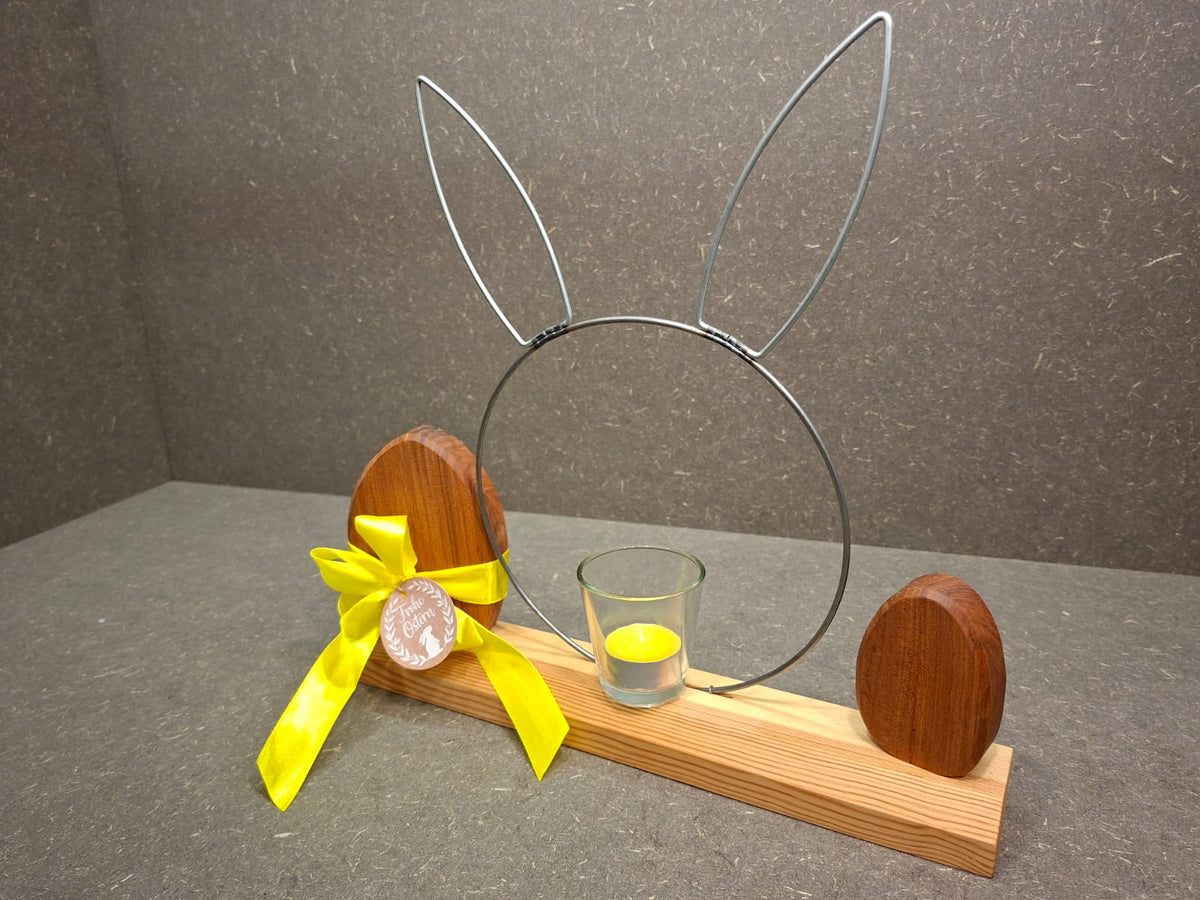 Handgefertigte Osterdekoration aus geölter Kiefer mit Metallhase, Kirscheiern und Teelichthalter. Gelbe Schleife und Teelicht.