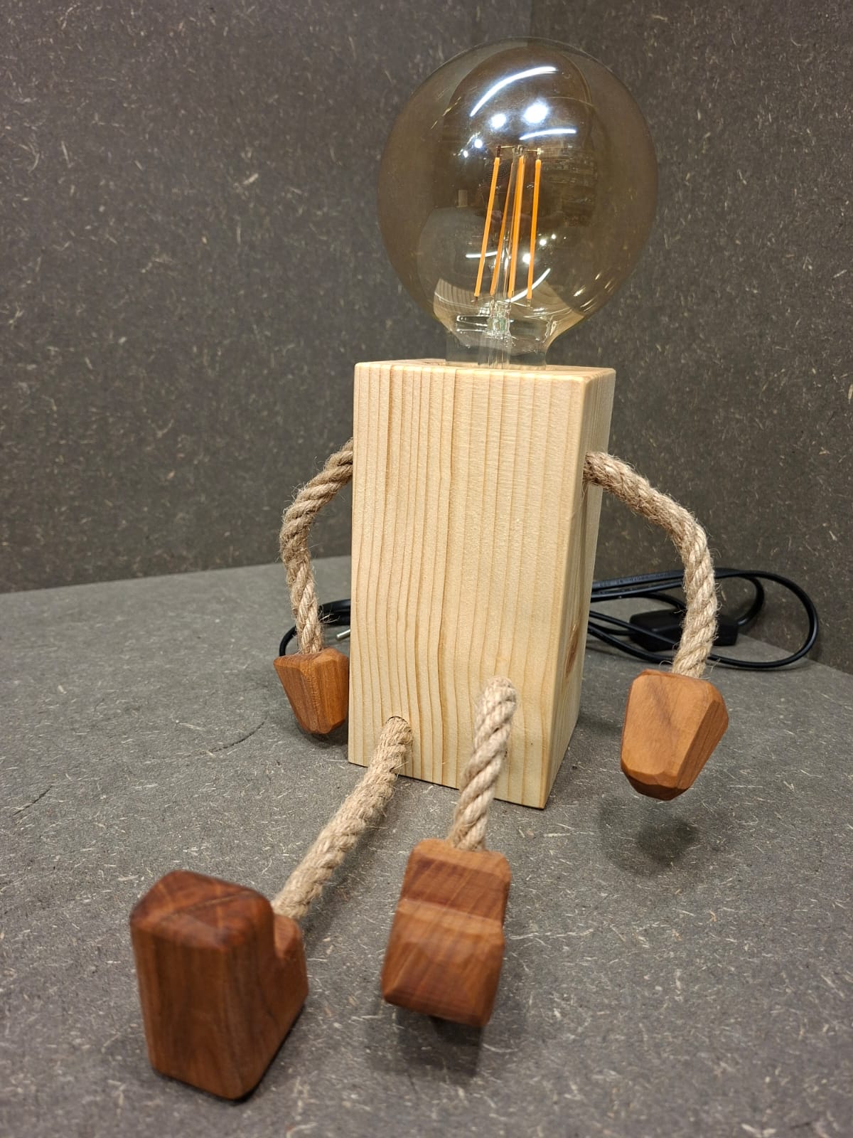 Handgefertigtes Lampen Männchen aus Fichte und Kirschholz mit beweglichen Seilarmen und -beinen als Tischlampe und Kantenhocker.