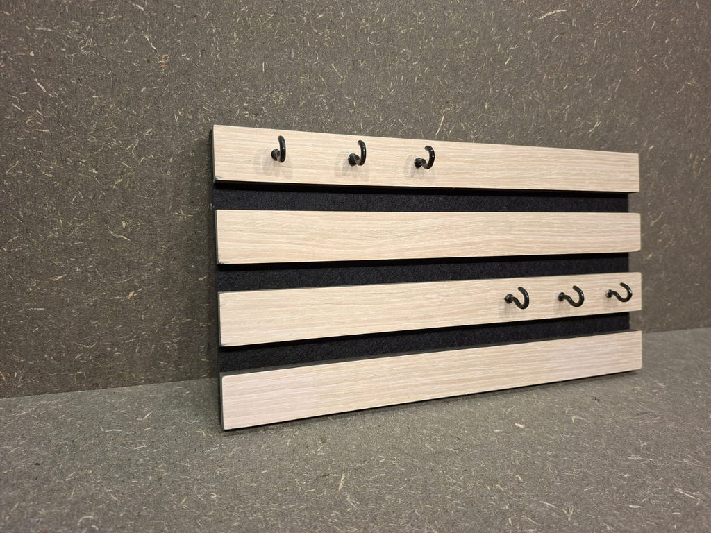 Modernes Schlüsselbrett aus weißem Akustikpaneel mit sechs Metallhaken.
