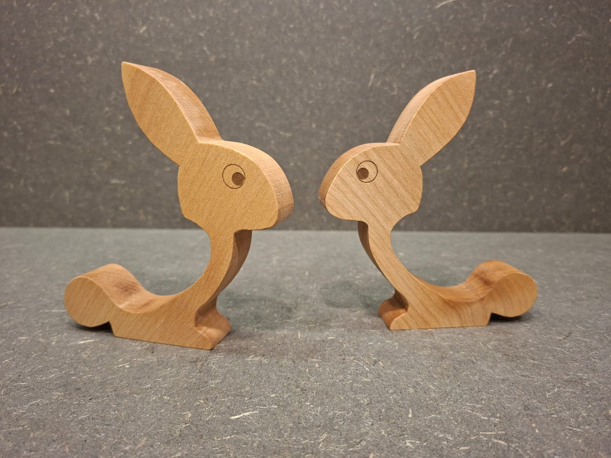 Handgefertigter Eierhalter aus geöltem Ahorn in Hasenform mit Ei auf dem Rücken als Osterdekoration.
