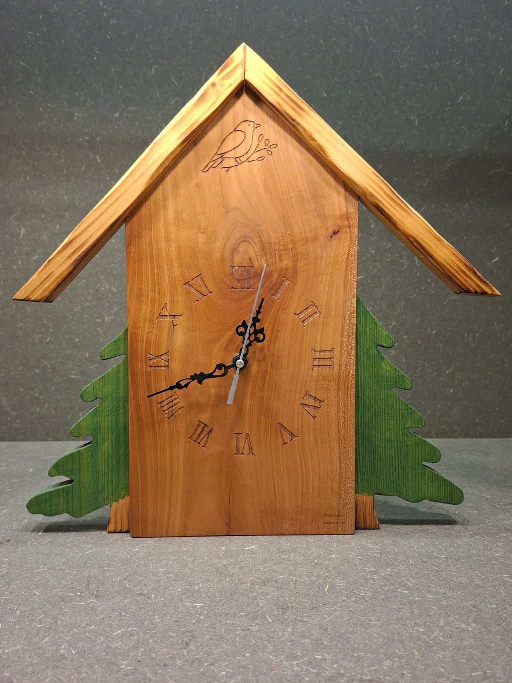 Handgefertigte Schwarzwaldhaus Wanduhr aus Birne und Kiefer mit grünen oder naturfarbenen Bäumen.
Bäume grün.