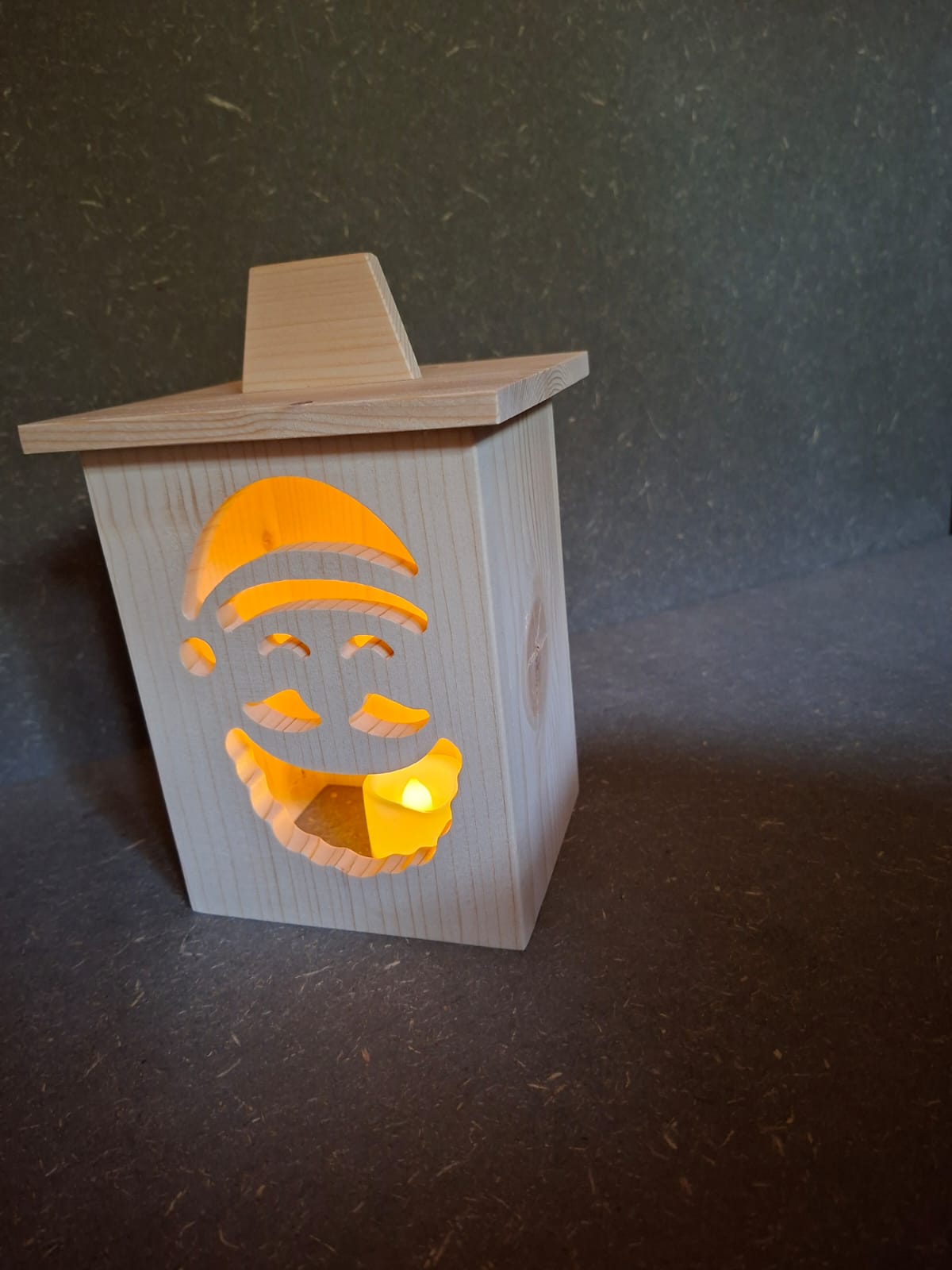 Drei handgefertigte LED-Weihnachtslaternen aus hellem Holz mit ausgesägten Motiven Weihnachtsmann, Tannenbaum und Kerze.
