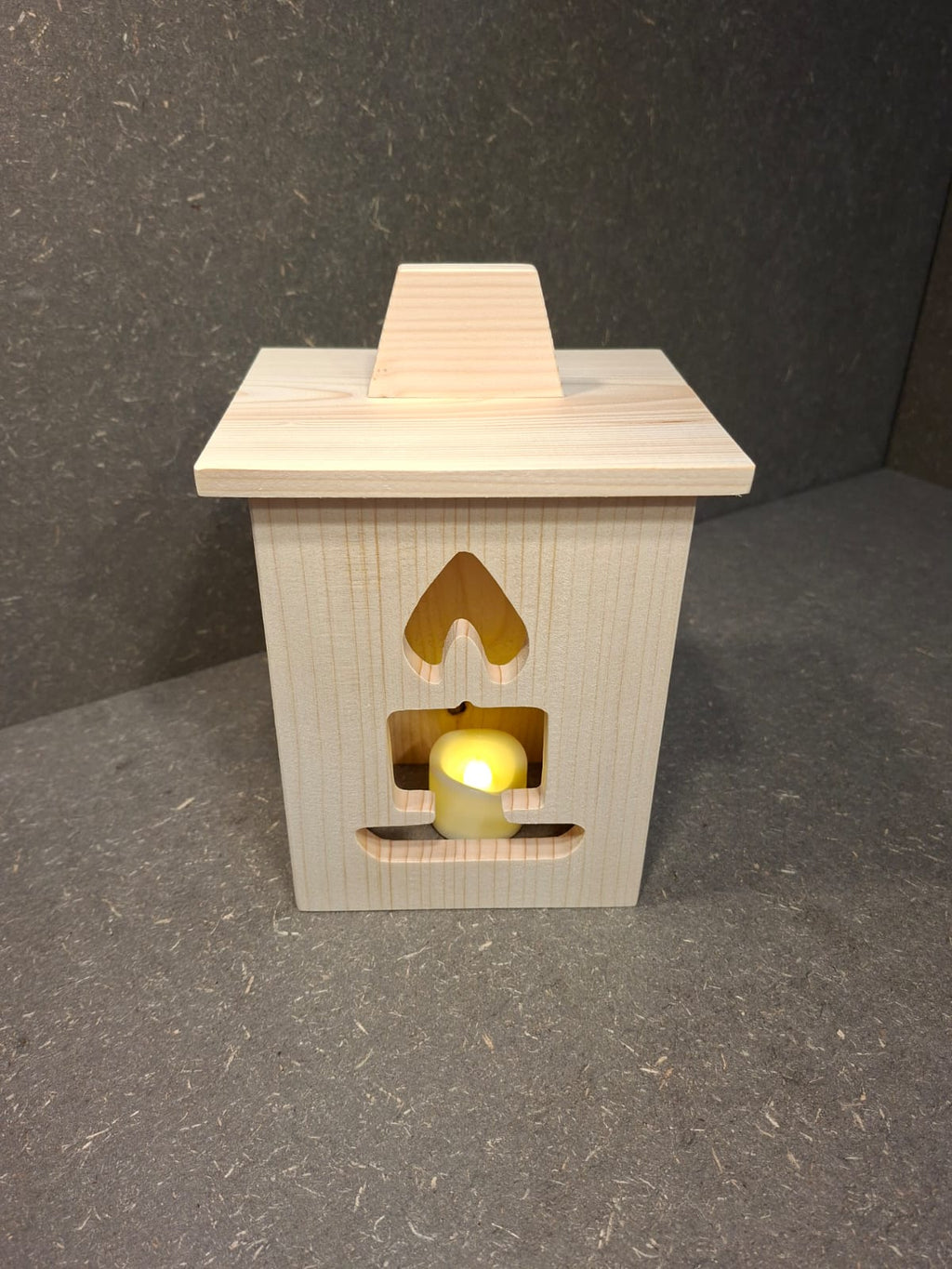 Drei handgefertigte LED-Weihnachtslaternen aus hellem Holz mit ausgesägten Motiven Weihnachtsmann, Tannenbaum und Kerze.