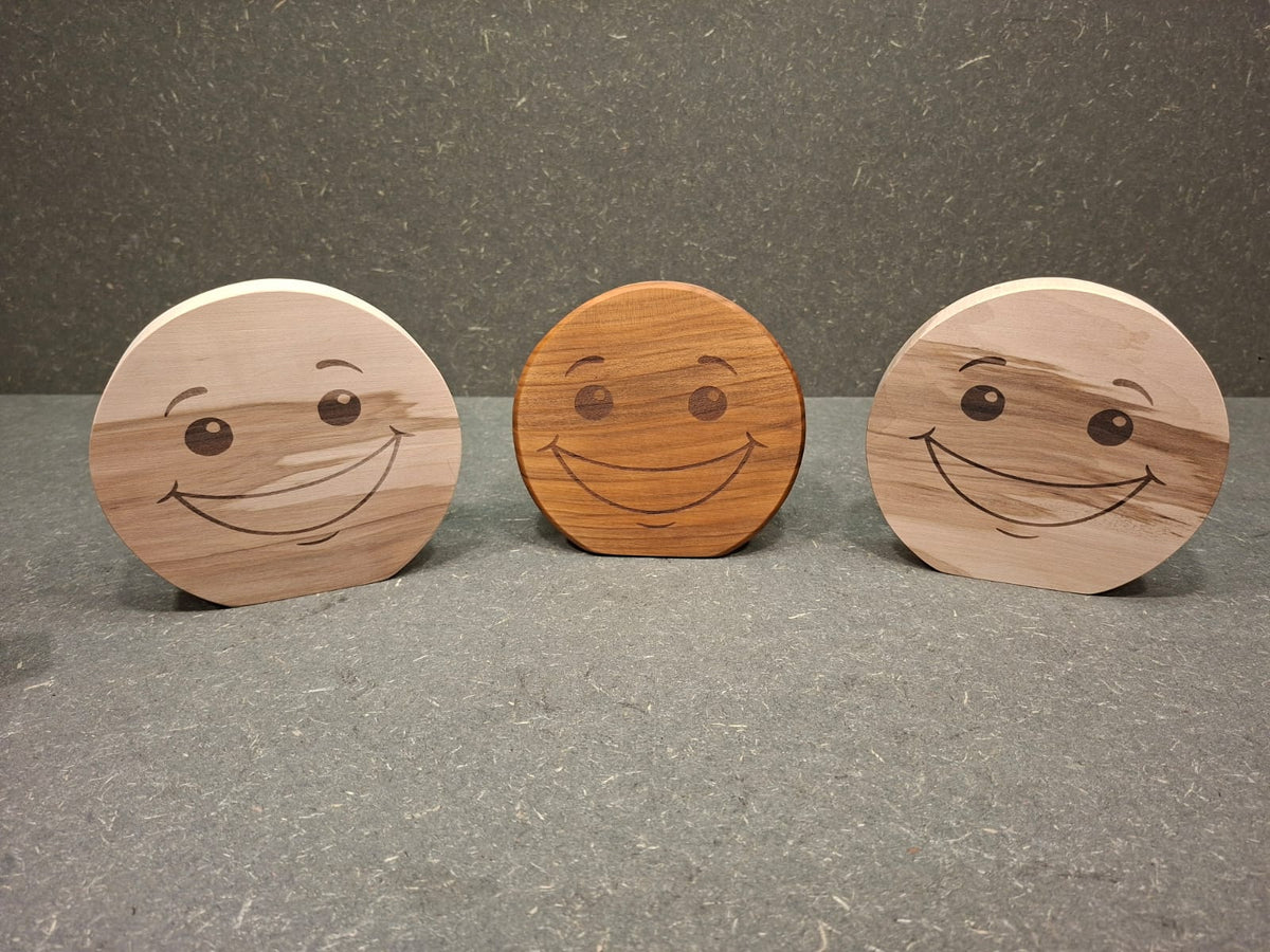 Handgefertigter Smiley aus Holz mit graviertem Gesicht und natürlicher Holzmaserung als dekorativer Holzaufsteller.