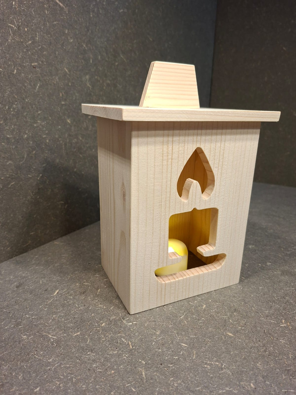 Drei handgefertigte LED-Weihnachtslaternen aus hellem Holz mit ausgesägten Motiven Weihnachtsmann, Tannenbaum und Kerze.