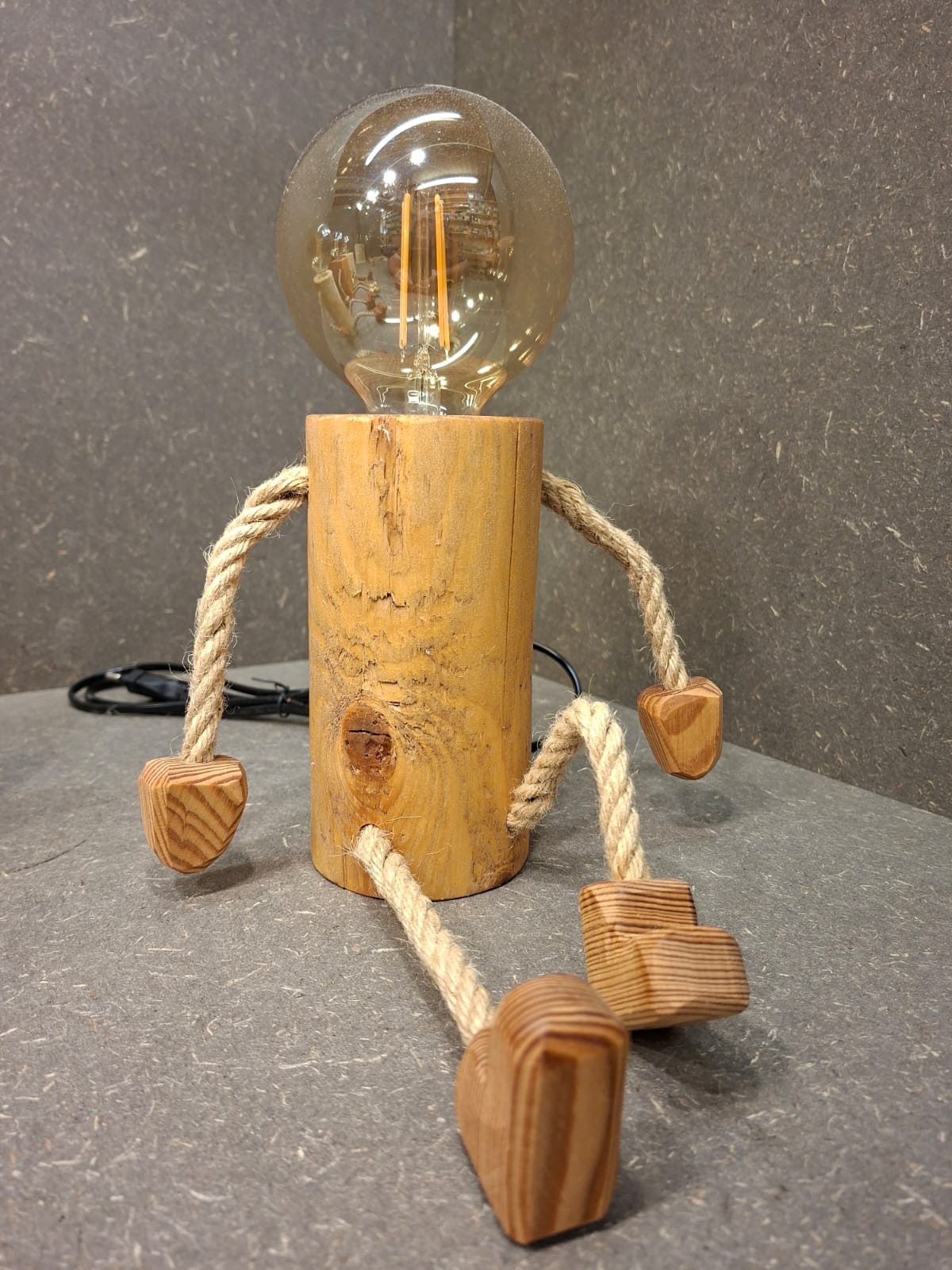 Handgefertigtes Lampen Männchen aus Fichte und Kirschholz mit beweglichen Seilarmen und -beinen als Tischlampe und Kantenhocker.