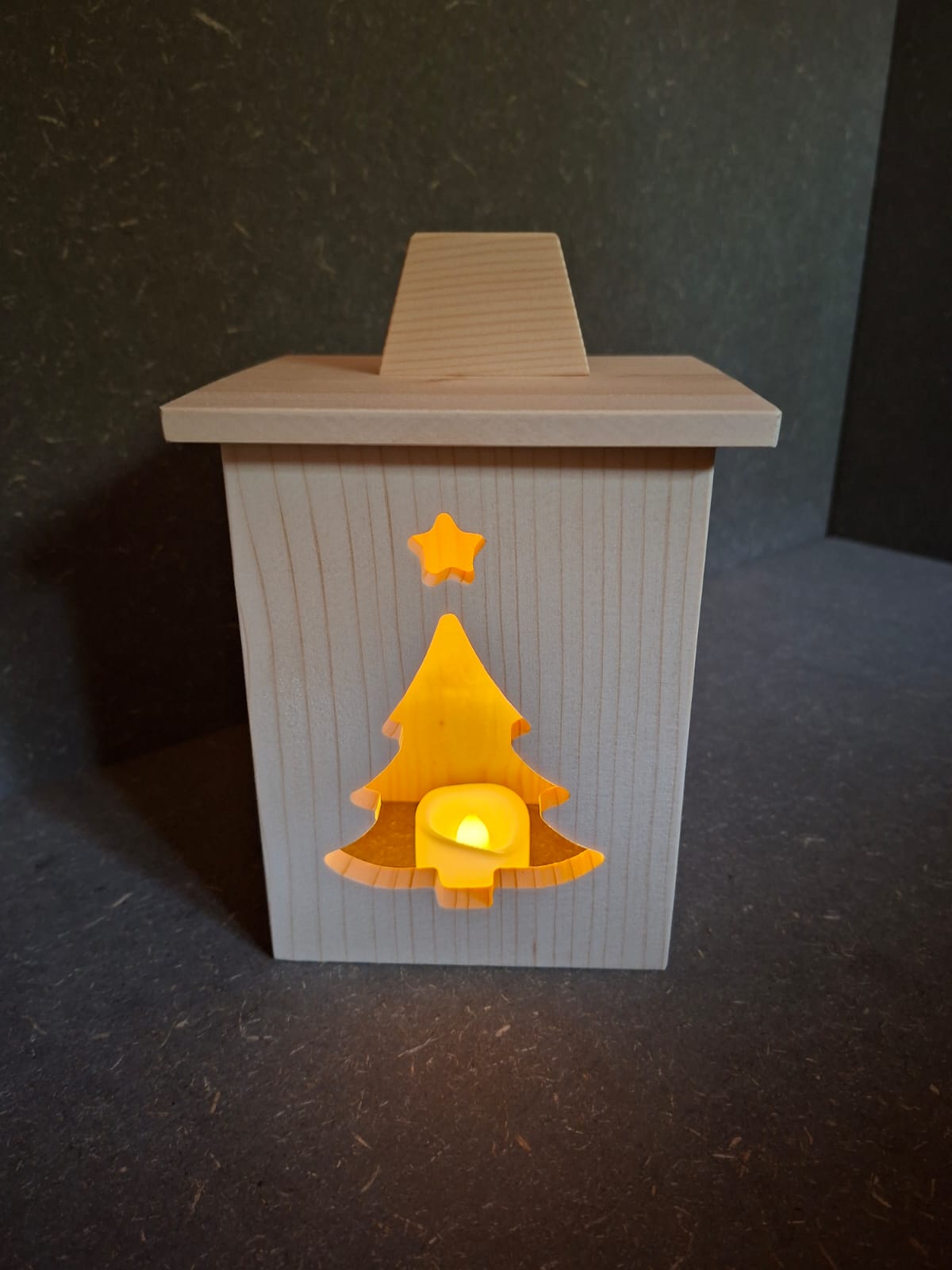 Drei handgefertigte LED-Weihnachtslaternen aus hellem Holz mit ausgesägten Motiven Weihnachtsmann, Tannenbaum und Kerze.