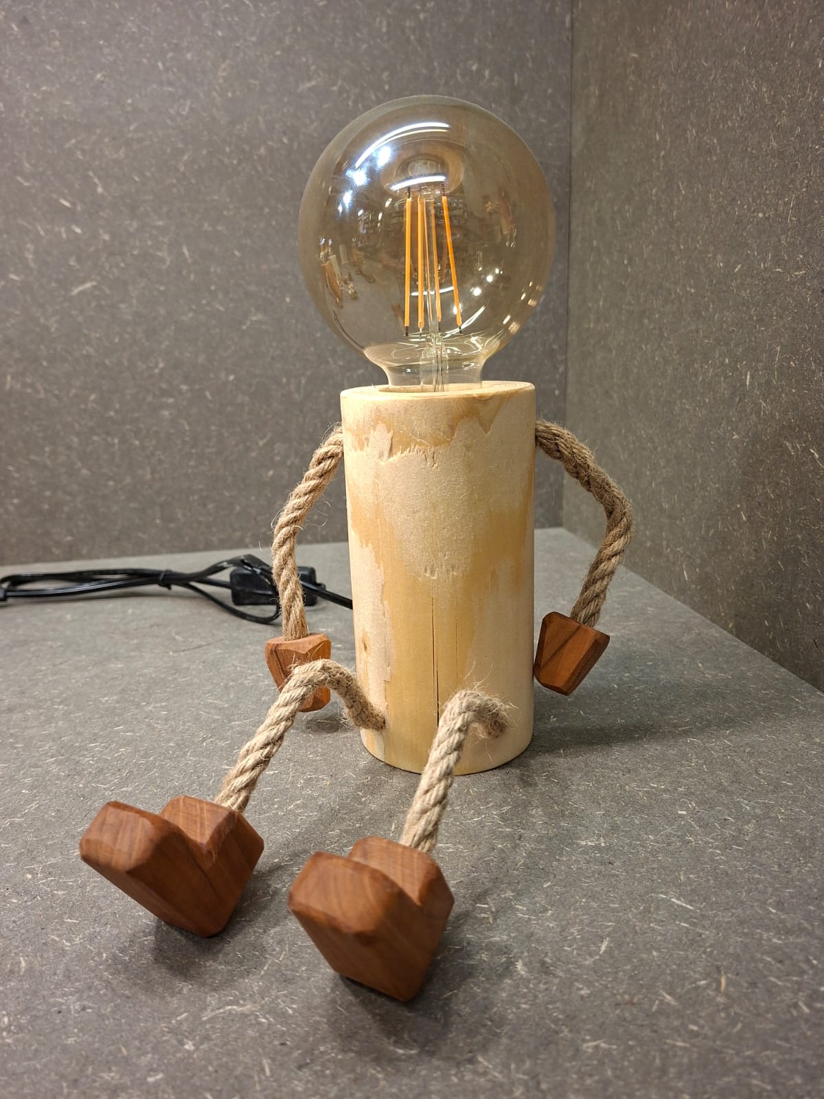 Handgefertigtes Lampen Männchen aus Fichte und Kirschholz mit beweglichen Seilarmen und -beinen als Tischlampe und Kantenhocker.