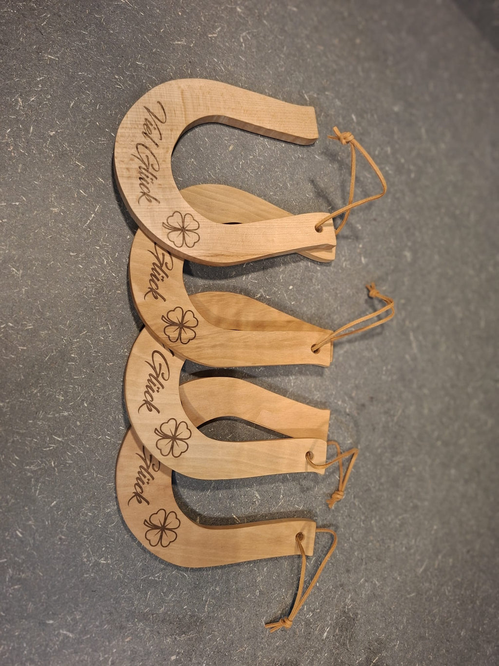 Handgefertigtes Hufeisen aus Holz – dekorativer Glücksbringer von Kieninger Produkte aus Holz. Auf dem Bild sind 4 Hufeisen zu sehen mit der Gravur Viel Glück 