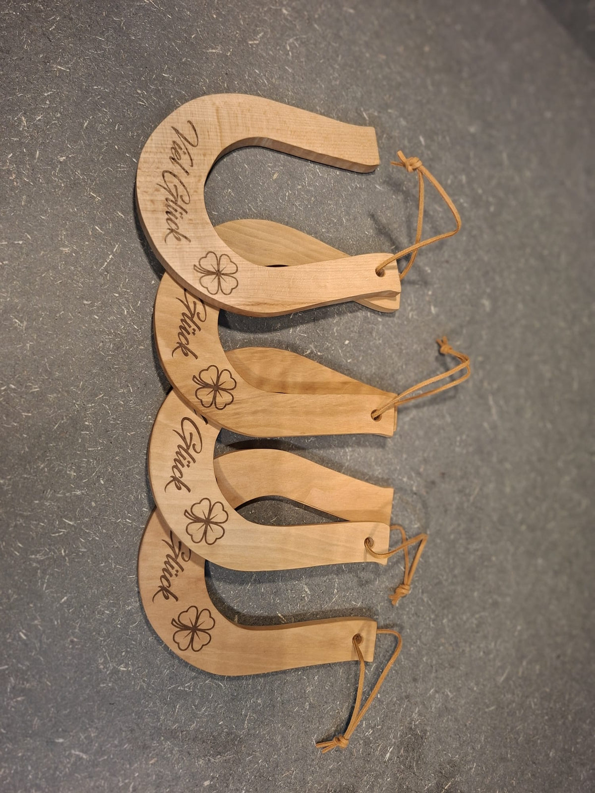 Handgefertigtes Hufeisen aus Holz – dekorativer Glücksbringer von Kieninger Produkte aus Holz. Auf dem Bild sind 4 Hufeisen zu sehen mit der Gravur Viel Glück 