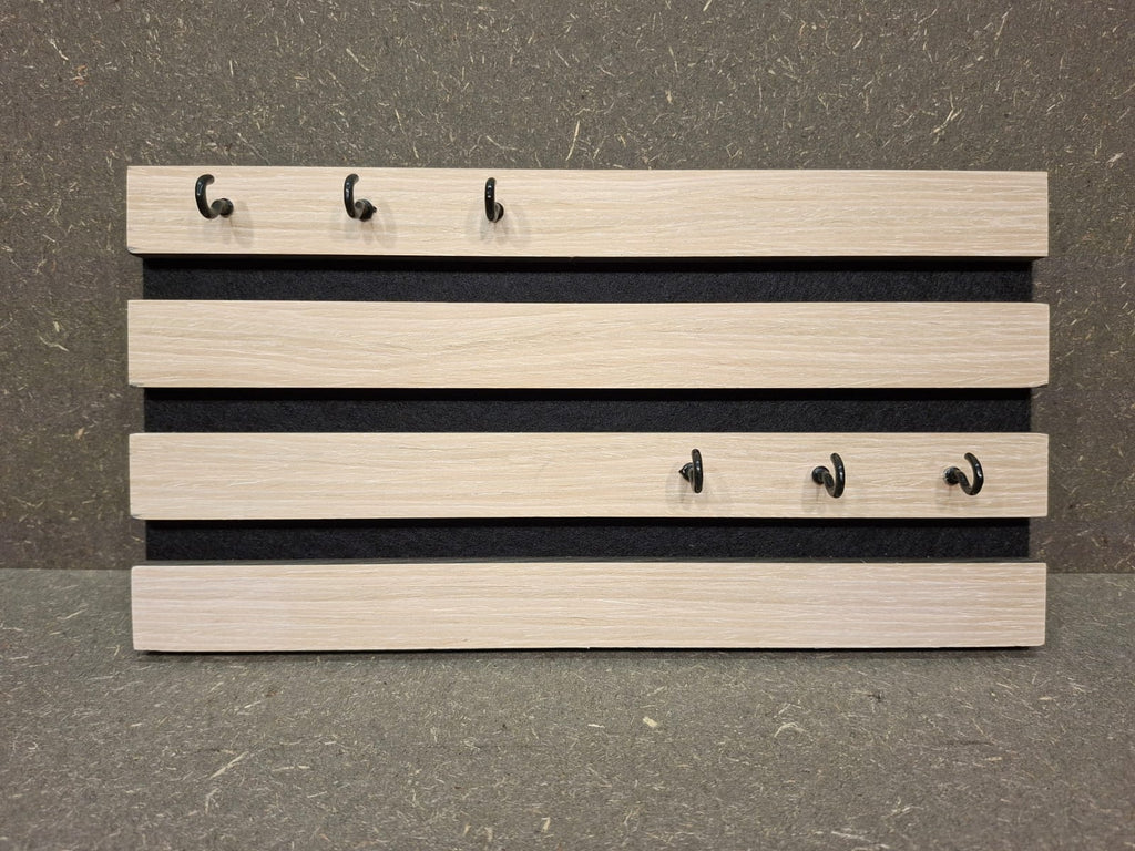 Modernes Schlüsselbrett aus weißem Akustikpaneel mit sechs Metallhaken.