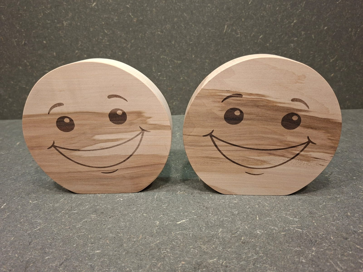 Handgefertigter Smiley aus Holz mit graviertem Gesicht und natürlicher Holzmaserung als dekorativer Holzaufsteller.