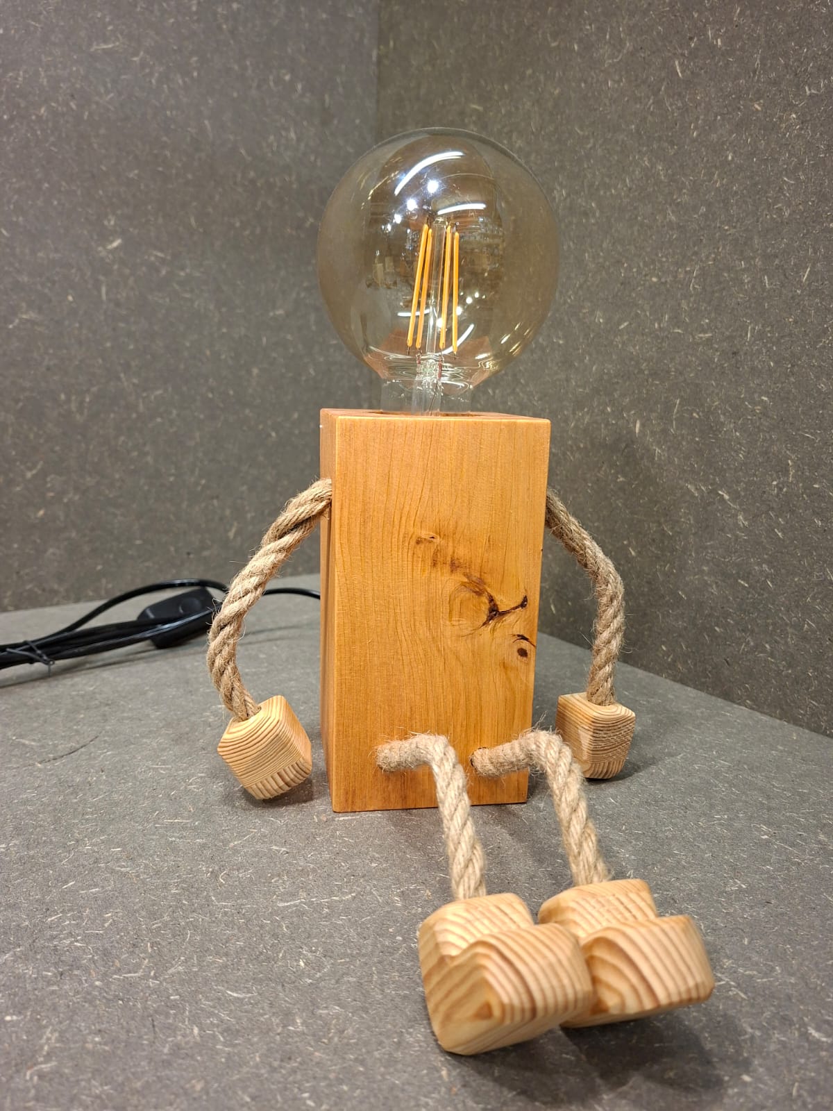 Handgefertigtes Lampen Männchen aus Fichte und Kirschholz mit beweglichen Seilarmen und -beinen als Tischlampe und Kantenhocker.