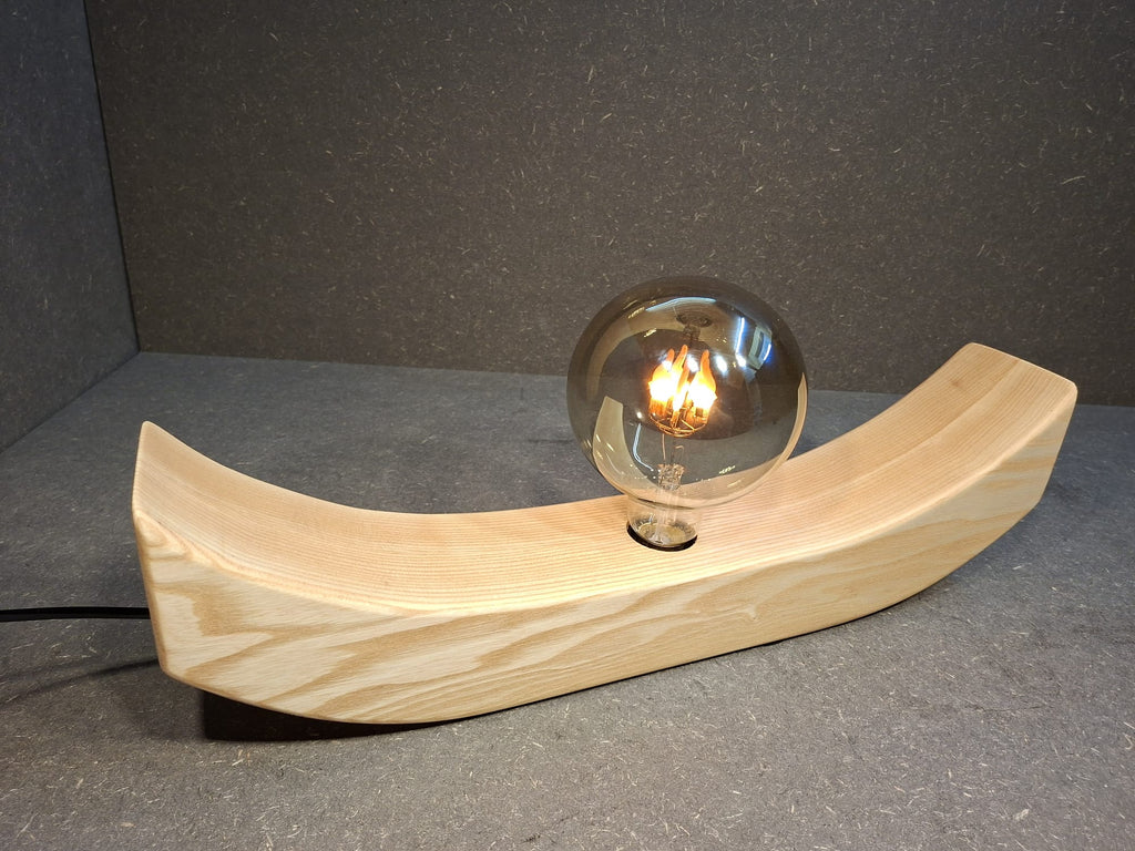 Handgefertigte Holzlampe Lichtbogen aus geöltem Eschenholz mit geschwungenem Sockel und leuchtender Glaskugel mit flackerndem Licht.