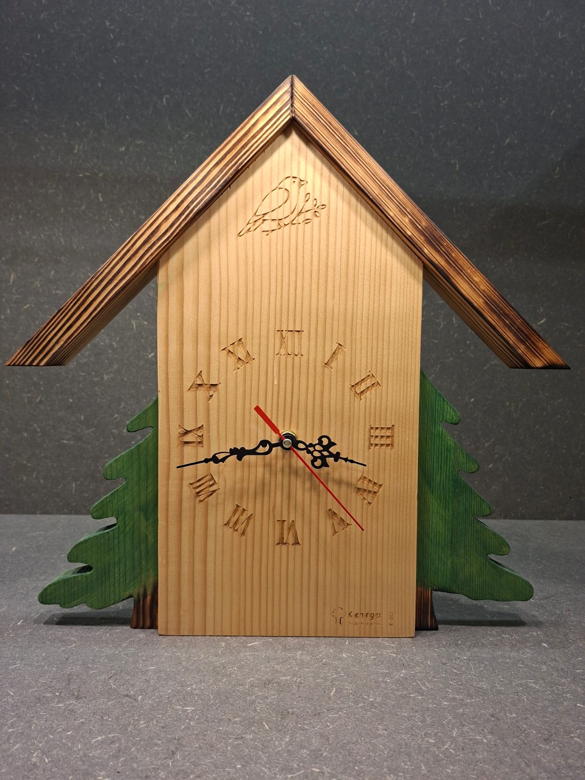 Handgefertigte Schwarzwaldhaus Wanduhr aus Birne und Kiefer mit grünen oder naturfarbenen Bäumen.
Bäume grün.