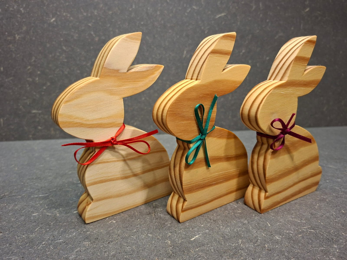Handgefertigter Hase aus geölter Kiefer mit Schleife als natürliche Osterdekoration.