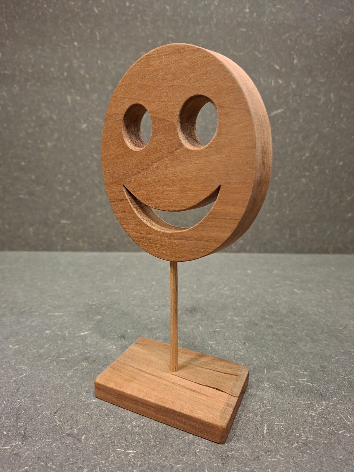 Handgefertigter Holz Smiley aus geöltem Birnenholz mit Holzstab und Standfuß als natürliche Dekoration.
