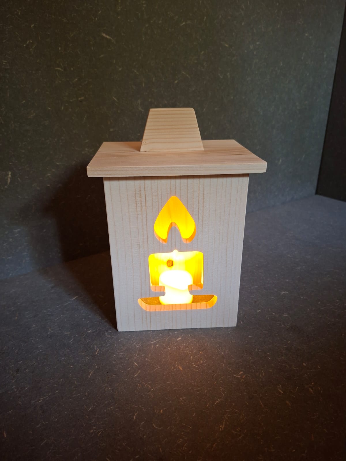 Drei handgefertigte LED-Weihnachtslaternen aus hellem Holz mit ausgesägten Motiven Weihnachtsmann, Tannenbaum und Kerze.