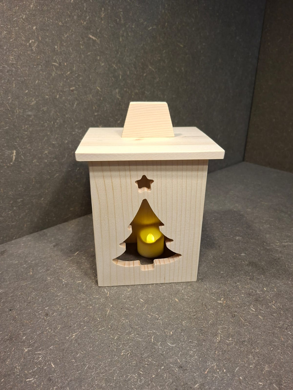 Drei handgefertigte LED-Weihnachtslaternen aus hellem Holz mit ausgesägten Motiven Weihnachtsmann, Tannenbaum und Kerze.