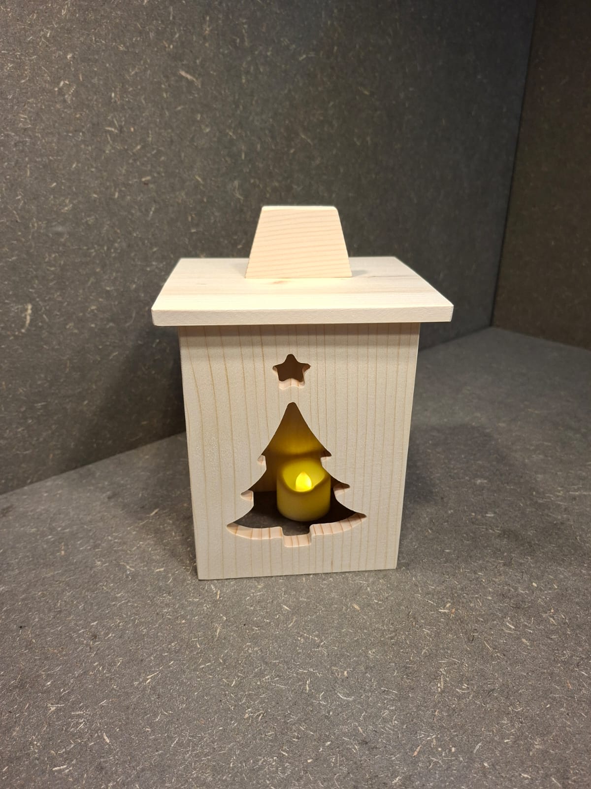 Drei handgefertigte LED-Weihnachtslaternen aus hellem Holz mit ausgesägten Motiven Weihnachtsmann, Tannenbaum und Kerze.