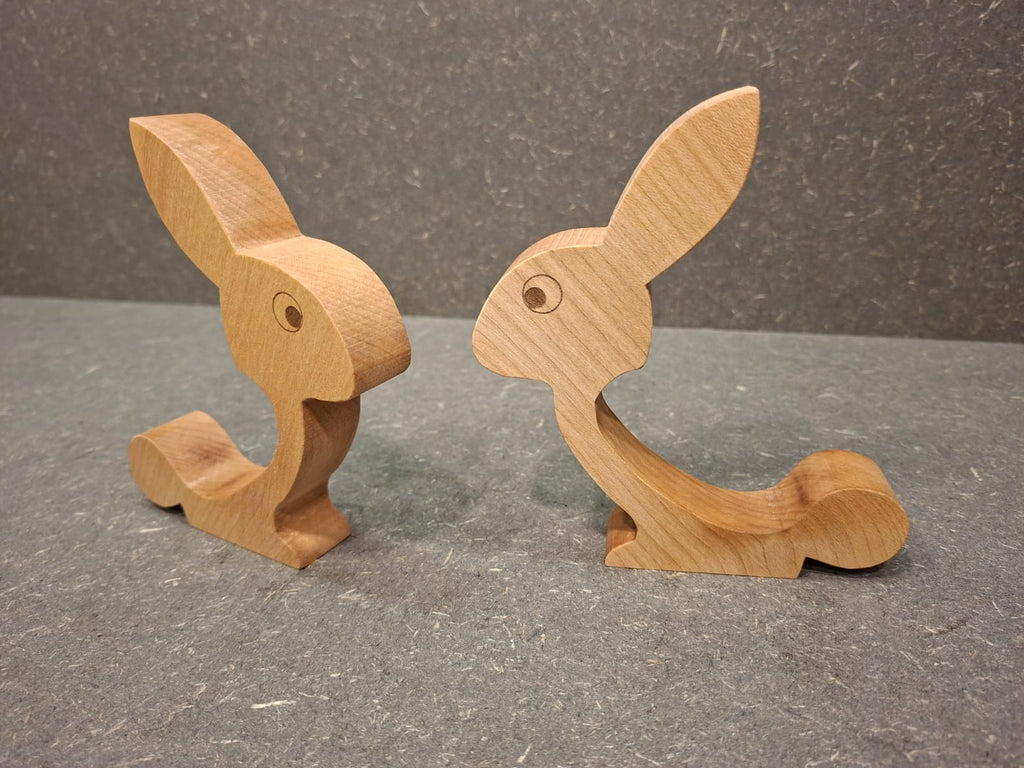 Handgefertigter Eierhalter aus geöltem Ahorn in Hasenform mit Ei auf dem Rücken als Osterdekoration.