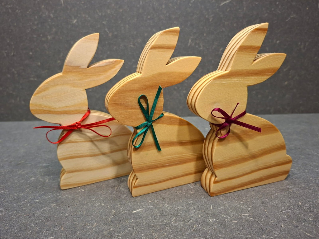 Handgefertigter Hase aus geölter Kiefer mit Schleife als natürliche Osterdekoration.