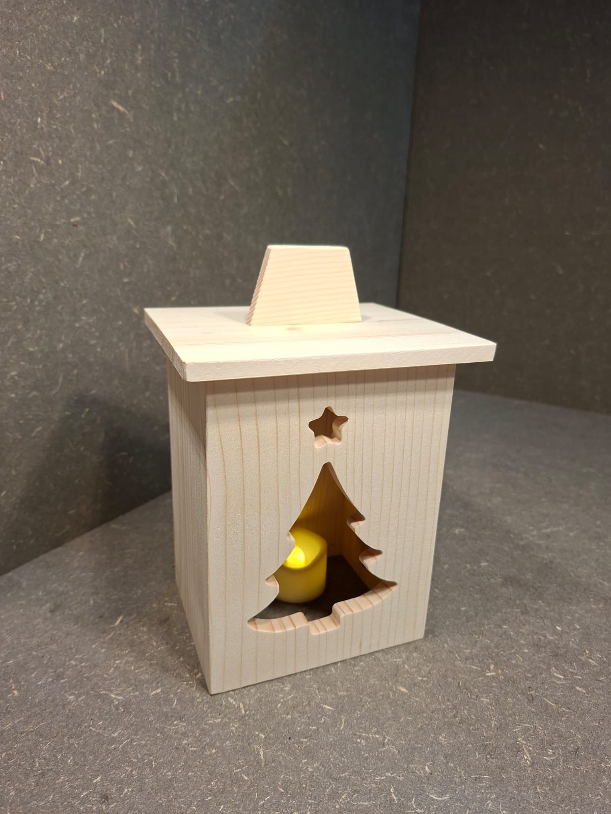 Drei handgefertigte LED-Weihnachtslaternen aus hellem Holz mit ausgesägten Motiven Weihnachtsmann, Tannenbaum und Kerze.
